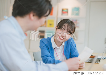 男性社員と笑顔で向き合う女子社員のデスクシーン 男性社員と笑顔で向き合う女子社員のデスクシーン 142422352