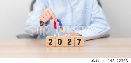 hand holding magnet and pulling man chess figure from the crowd employee with 2027 Year block. Human resource management, Recruitment, Teamwork, strategy, toxic people and leadership Concepts 142422388
