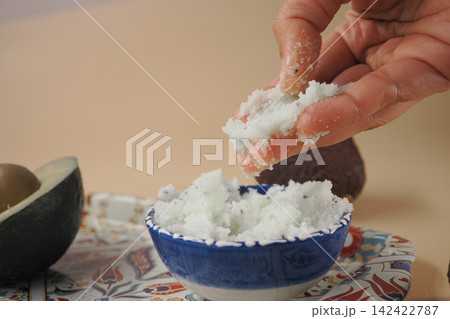 Hand pick avocado scrub from a bowl Hand pick avocado scrub from a bowl 142422787