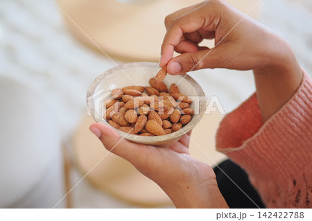 Eating almonds from a bowl in a cozy setting Eating almonds from a bowl in a cozy setting 142422788