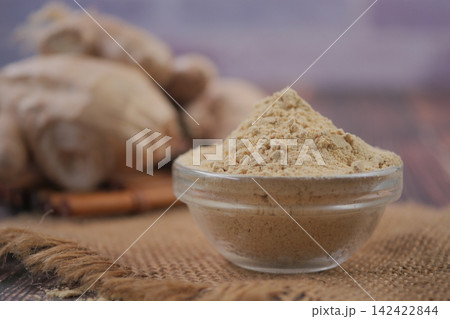 Ginger powder in clear bowl on rustic table 142422844