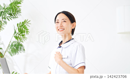 胸に手を当てる白衣の女性。看護師、介護士、病院、受付、信頼、安心、保険、お任せ、自信、依頼、接客 胸に手を当てる白衣の女性。看護師、介護士、病院、受付、信頼、安心、保険、お任せ、自信、依頼、接客 142423706