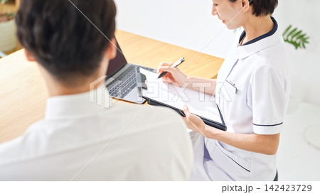 問診する白衣の女性。看護師、医師、産業医、相談、面談、診察、診療、健診、受付、クリニック、薬剤師 問診する白衣の女性。看護師、医師、産業医、相談、面談、診察、診療、健診、受付、クリニック、薬剤師 142423729