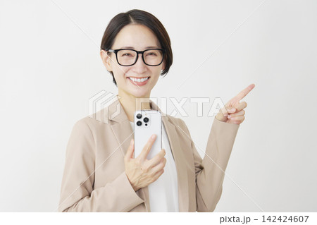 スマホを持って右側を指差すビジネスウーマン ミドル 白背景 スマホを持って右側を指差すビジネスウーマン ミドル 白背景 142424607