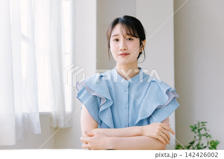 部屋で腕組みをする若い女性 部屋で腕組みをする若い女性 142426002