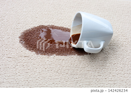 A white coffee mug creating a large brown stain on carpet. A white coffee mug creating a large brown stain on carpet. 142426234