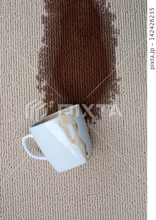 A white coffee mug creating a large brown stain on carpet. A white coffee mug creating a large brown stain on carpet. 142426235