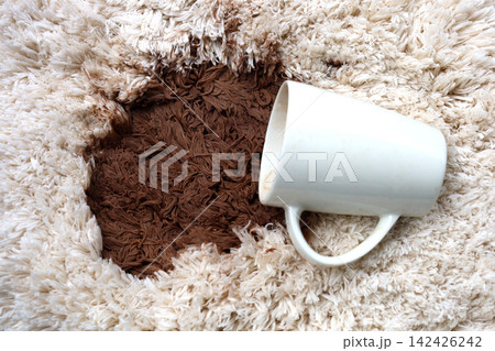 A white coffee mug creating a large brown stain on carpet. A white coffee mug creating a large brown stain on carpet. 142426242