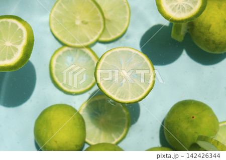Fresh whole and sliced limes floating in clear water. 142426344