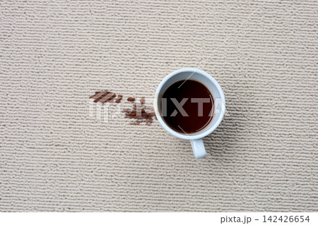 A white ceramic coffee mug sits on the carpet with a dark brown stain. A white ceramic coffee mug sits on the carpet with a dark brown stain. 142426654