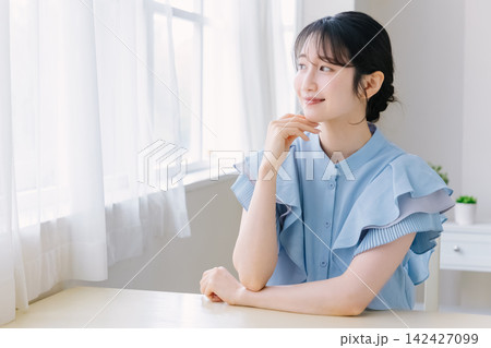 頬杖をつく若い女性 142427099