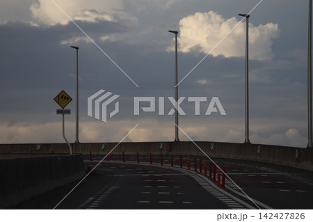 カーブする道路と街灯と雲の多い空の風景 142427826
