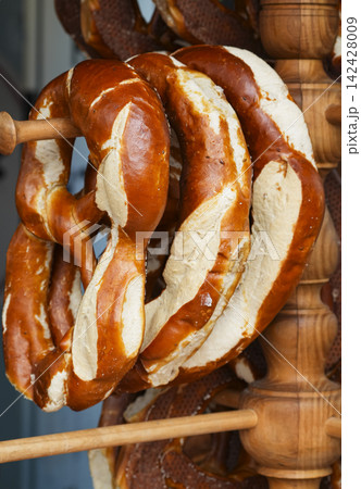 Fresh baked pretzels hanging on a wooden rack in a bakery, illustrating a rustic wooden pretzel stand. Fresh baked pretzels hanging on a wooden rack in a bakery, illustrating a rustic wooden pretzel stand. 142428009