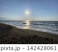 休日の午後、砂浜で海に沈む夕日を見つめる 142428061