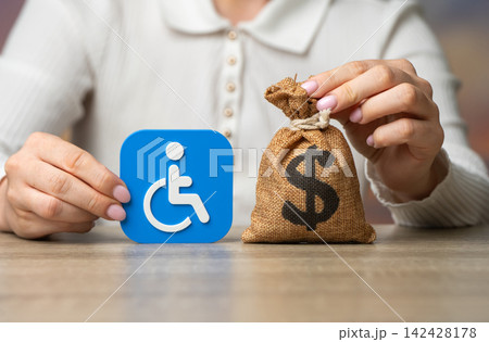 Disability symbol and dollar money bag. Compensation for health damage, medical treatment grants, pensions and benefits. Social support and financial assistance. Disability symbol and dollar money bag. Compensation for health damage, medical treatment grants, pensions and benefits. Social support and financial assistance. 142428178