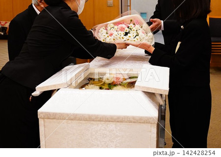 棺にお別れの花束をのせる家族 142428254