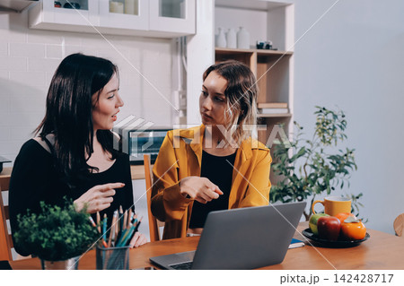 Portrait of military mother helping teen daughter with homework and eating lunch Portrait of military mother helping teen daughter with homework and eating lunch 142428717
