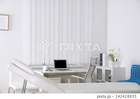Doctor's office interior with desk and examination couch 142428833
