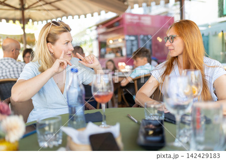 Women communicating using sign language at restaurant outdoors 142429183