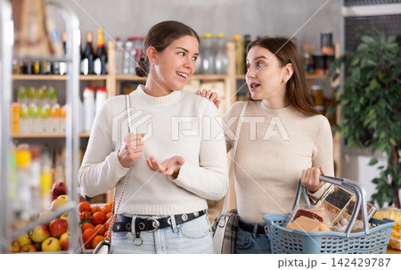 Two friends choose and buy groceries together in the grocery department of supermarket Two friends choose and buy groceries together in the grocery department of supermarket 142429787