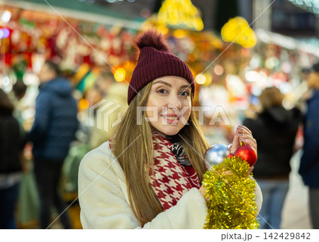 Young woman has purchased decorations for Christmas tree, tinsel and colorful balls 142429842