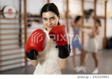 Woman in red boxing gloves in gym Woman in red boxing gloves in gym 142429901