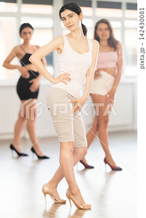 Graceful women blending sensuality with fashion while partaking in group high heels dance class 142430081