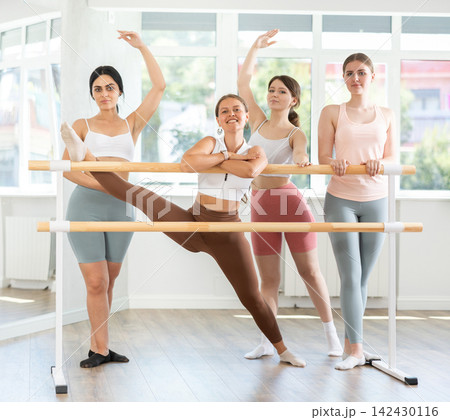 Young attendees of ballet courses posing by ballet barre 142430116
