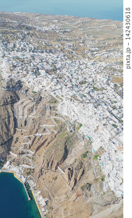 Aerial view of Santorini showcasing whitewashed buildings, winding pathways, and the Aegean Sea, highlighting the unique architecture and landscape of this iconic Greek island destination Aerial view of Santorini showcasing whitewashed buildings, winding pathways, and the Aegean Sea, highlighting the unique architecture and landscape of this iconic Greek island destination 142430618
