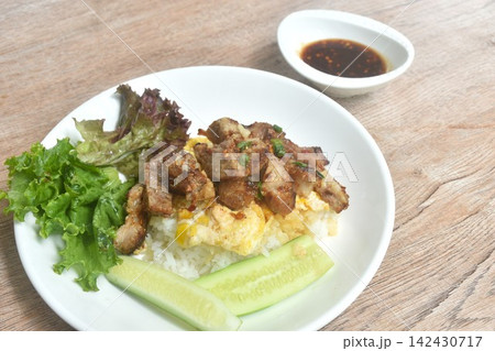 grilled pork dipping spicy chili tamarind Thai sauce with fried cream egg omelet and vegetable salad on rice in plate 142430717