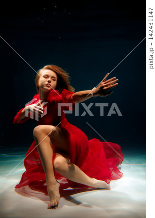 Caucasian actress underwater in red dress, expressive performance Caucasian actress underwater in red dress, expressive performance 142431147