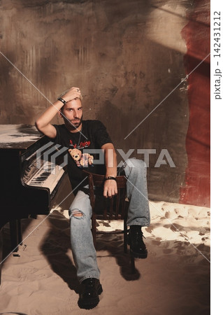 Casual male guitarist practicing amidst dim studio lighting and shadows Casual male guitarist practicing amidst dim studio lighting and shadows 142431212