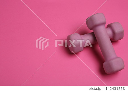 Modern dumbbells on pink background. Space for text 142431258