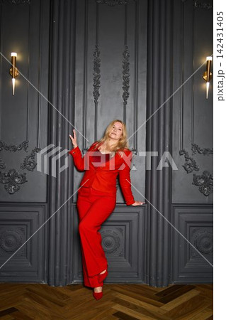 Refined white woman in red suit facilitates elegant social gathering 142431405