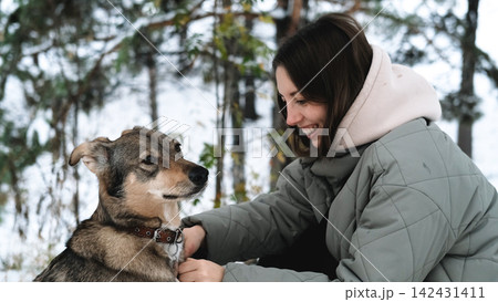 A young woman walks through a winter pine forest with her dog 142431411