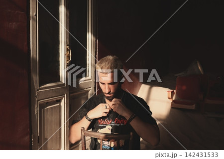 Contemplative young musician sits calmly with focused expression Contemplative young musician sits calmly with focused expression 142431533
