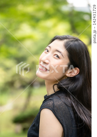 夏の緑の公園で肩越しに見上げる20代の日本人女性 夏の緑の公園で肩越しに見上げる20代の日本人女性 142431729