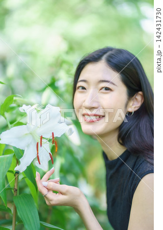 夏の庭で白いユリのそばに微笑む20代の日本人女性 142431730