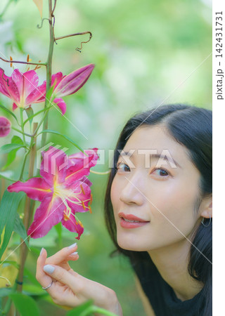 夏の庭で咲くピンクのユリのそばにたたずむ20代の日本人女性 夏の庭で咲くピンクのユリのそばにたたずむ20代の日本人女性 142431731