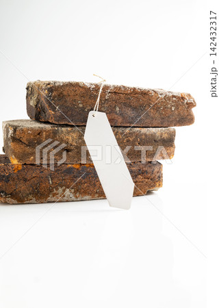 Three stacked rustic weathered bricks with a blank white label hanging on a string, isolated on a white background. Mockup or Copyspace Three stacked rustic weathered bricks with a blank white label hanging on a string, isolated on a white background. Mockup or Copyspace 142432317