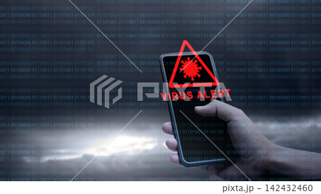 A hand holding a smartphone showing a red 'VIRUS ALERT' warning icon, set against a dark background with digital binary code. Concept of Technology Security 142432460