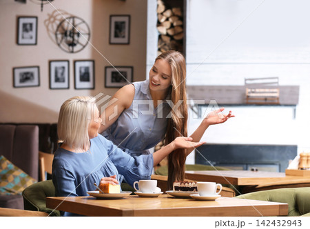 Mother and her adult daughter spending time together in cafe Mother and her adult daughter spending time together in cafe 142432943