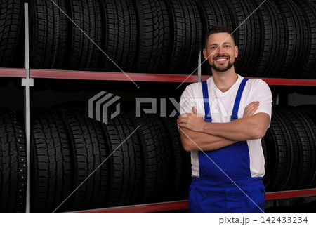 Male mechanic near rack with car tires in auto store Male mechanic near rack with car tires in auto store 142433234