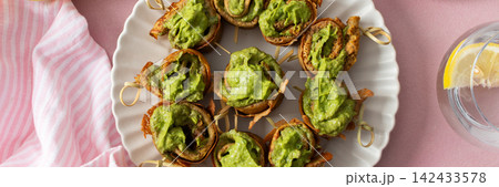 A group of pesto pancake rolls sits on white plates with a small bowl of sauce nearby. Lemon slices decorate the table, and a glass of water is present during breakfast time, banner A group of pesto pancake rolls sits on white plates with a small bowl of sauce nearby. Lemon slices decorate the table, and a glass of water is present during breakfast time, banner 142433578