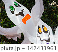 A close view of glowing inflatable ghosts highlights cheerful Halloween decorations. The illuminated display adds festive charm to an outdoor holiday setting. 142433961