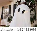 A friendly ghost decoration with glowing lights stands in front of a home during Halloween. The festive display creates a playful seasonal atmosphere. 142433966