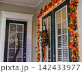 A front entrance is decorated with colorful autumn garlands, glowing string lights, and a festive Halloween wreath. The seasonal display creates a warm and welcoming atmosphere for visitors. 142433977