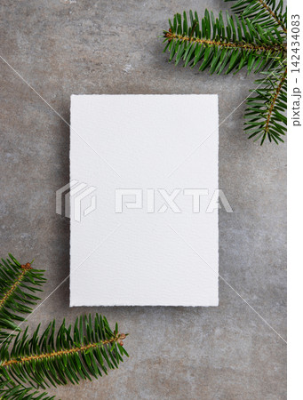 Blank vertical Christmas card mockup near green fir branches on grey stone. Rustic holiday scene Blank vertical Christmas card mockup near green fir branches on grey stone. Rustic holiday scene 142434083