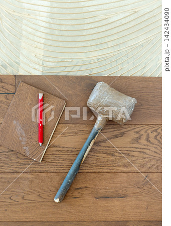 Rubber mallet and pencil on brown oak parquet planks during hardwood flooring installation 142434090