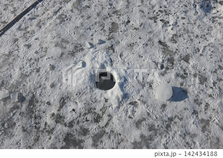 Ice Fishing Hole on Snowy Surface 142434188